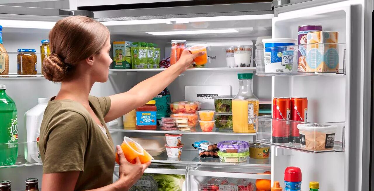 open refrigerator woman putting food